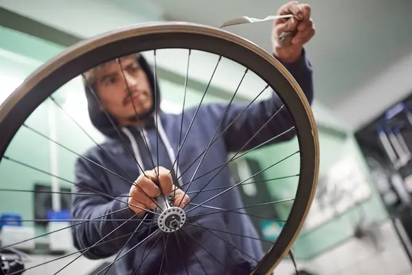 Hispanic man working on a bike painting. Time to remove the masking tape of the wheel rim. Close up view of the hands.