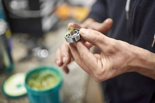 Unrecognizable person greasing a bicycle bearing in his bike workshop as part of a maintenance service. Real people at work.