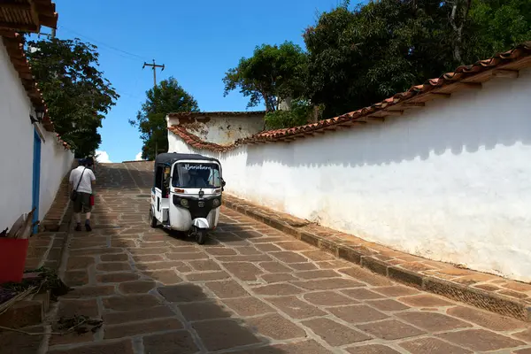 Barichara, Santander, Kolombiya; 25 Kasım 2022: Beyaz mototaxi, rickshaw, bu kasabada yaygın bir nakliye aracı, köyün merkezindeki sömürge kaldırımlı caddelerden geçiyor..