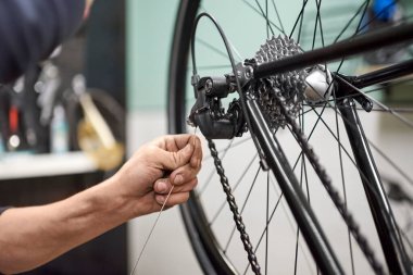 Bisiklet tamircisinin dükkanında yaptığı bakım hizmetinin bir parçası olarak bir bisikletin fren ve vites sistemini monte etmesi tanınmaz hale geldi. İş yerindeki gerçek insanlar.