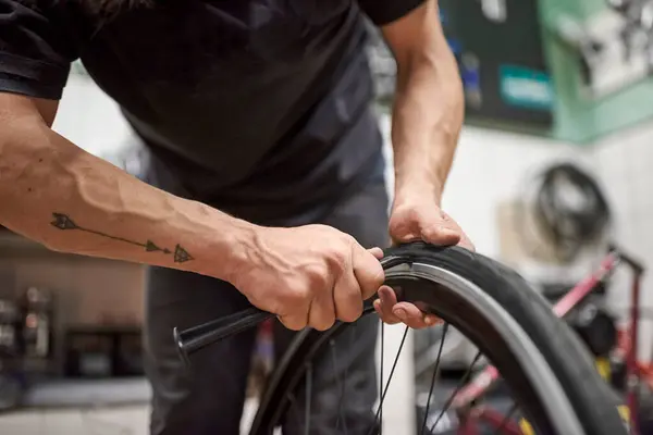 Stock image Unknown bicycle repairman installing an airless solid tire on a bike wheel at a repair shop. Selective focus composition with copy space.