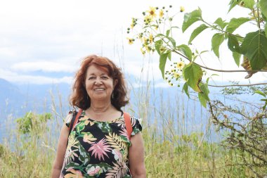 Aktif, olgun İspanyol kadın kameraya bakıp gülümsüyor, Kolombiya 'nın en güzel kasabası olan Barichara yakınlarındaki doğal bir alanda yürüyüş yapıyor..