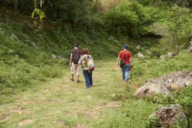 Tanınamayan üç yetişkinden oluşan bir aile, Kolombiya 'nın Santander kentinde Barichara ve Guane arasında yapılan tarihi ve turistik bir yürüyüşten keyif alıyor..