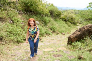 Santander, Kolombiya 'da, Barichara' dan Guane 'e giden ve restore edilmiş taştan kraliyet yolunda yürüyüş yapan olgun İspanyol bir kadın. Kavram: Doğayla temasta aktif ve sağlıklı yaşam tarzı.