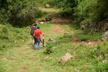 Bir baba ve yetişkin oğlunun tarihi kırsal bir patika boyunca yürüdüğünü görmek, yenilenmiş bir taş kraliyet yolu, Santander, Kolombiya 'da, Barichara' dan Guane 'e gidiyor..