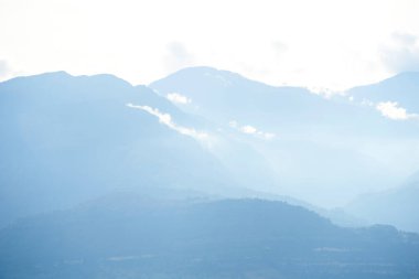 Bulutlar ve sis arasında görünen dağlar, Kolombiya Andean manzarası.