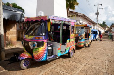 Guane, Santander, Kolombiya; 26 Kasım 2022: kasabanın ana meydanında turistleri bekleyen renkli motosiklet taksi kuyruğu. Bu turistik bölgede resmi ve yaygın bir ulaşım aracıdır.