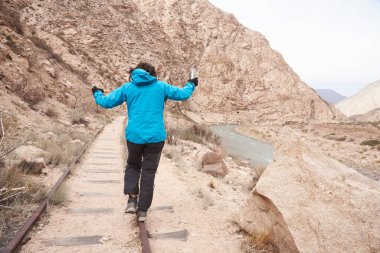 Arjantin 'in Potrerillos kentindeki dağlık bir arazide dengede yürüyen bir kadın görülüyor. Sağda Mendoza Nehri var..