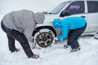 Kış zamanı, bir çift tanınmayan arkadaş, bir erkek ve kadın, bir SUV aracının tekerleklerine zincir takarak, bir dağ yolunda kar üzerinde ilerleyebilmek için.