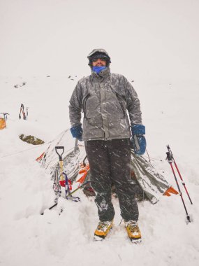 Karlı bir dağ manzarasında kar yağışı sırasında Arjantin, Mendoza 'da çadırının önünde duran bir adam..