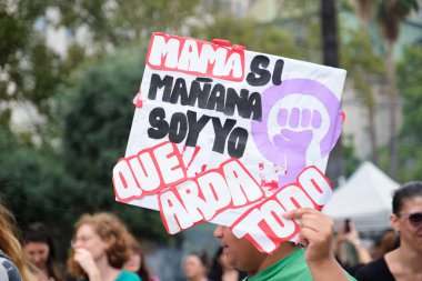 Buenos Aires, Arjantin; 8 Mart 2025: Uluslararası Kadınlar Günü. Kadının elinde feminist mücadele sembolü ve güçlü bir mesaj var: Anne, eğer yarın ben olacaksam, bırak hepsi yansın..