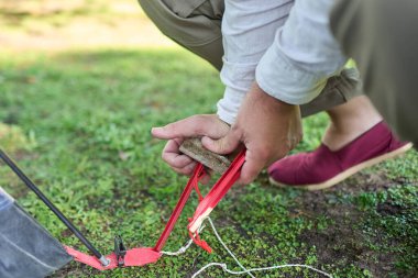 Kampta kurduğu çadırdan çadır çivisi çakmak için taşı çekiç olarak kullanan tanınmayan biri..