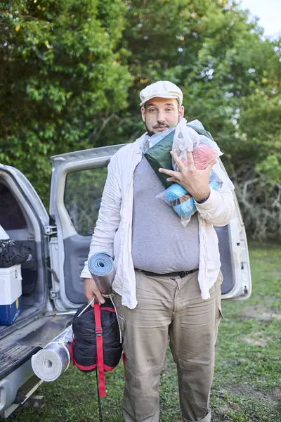 Yorgun gezgin kampını kurmak için kamp malzemelerini akşam karanlığında arabadan çıkarıyor..