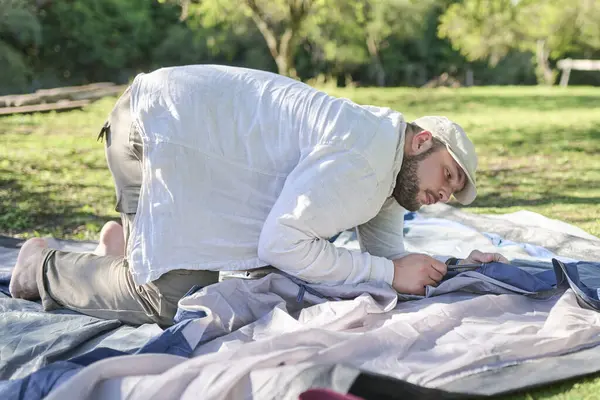 Çadırını doğal, sessiz, yeşil ve güneşli bir kamp alanına kuran bir adam..