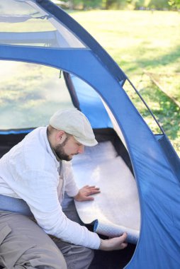 Genç gezgin çadırının içinde, yalıtım örtüsünü açıyor, kamp alanında kamp yaparken rahatça dinleniyor..