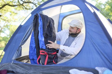 Genç İspanyol gezgin, mavi çadırının içinde kamp yaparken uyku tulumunu çıkartıyor..