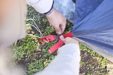 Tanınmayan bir adam çadırını yağmur gibi kuruyor, gün batımında, dışarıda kuruyor..