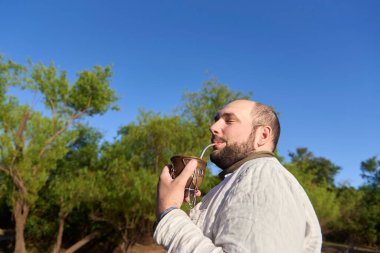 İspanyol adam dışarıda kaliteli zaman geçirir. Geleneksel bir Arjantin aşısı olan içki eşinin tadını çıkarır. El Palmar Ulusal Parkı, Entre Rios, Arjantin.
