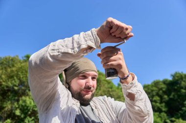 İspanyol adam gülerek kavrulmuş kahve çekirdeklerini öğütüyor. Seyahat öğütücüsüyle kampta güne başlamak için uyarıcı bir içecek hazırlıyor..