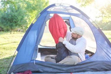 Genç İspanyol gezgin, dışarıda kamp yaparken mavi çadırının içinde bir uyku tulumu çıkardı..