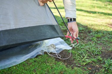 Tanınmayan bir adam çadırının direklerini kuruyor, onu dışarı kurarken..