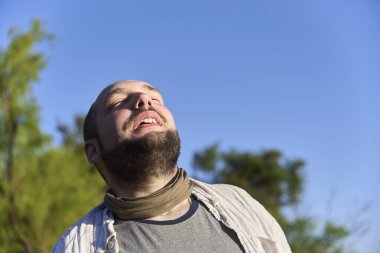 Sakin ve barışçıl bir ifadeyle gülümseyen genç bir adamın samimi portresi sabah güneşinin ışığıyla aydınlandı. Sahne, refahı, sükuneti ve olumlu duyguları iletir..