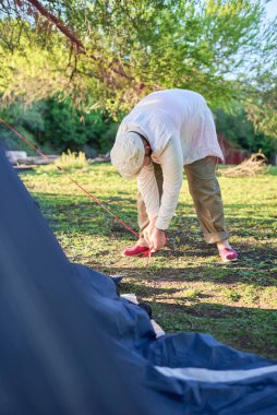 Tanınmayan erkek gezgin, hava kararırken çadırının gerilimini yağmur gibi ayarlar..