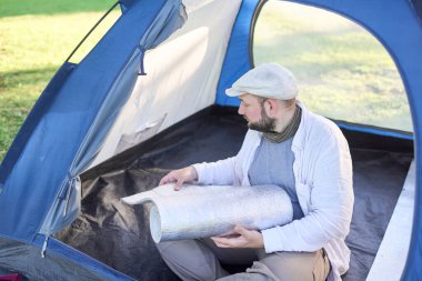 Genç gezgin, yalıtım paspaspasını vahşi bir kamp alanında kamp yaparken çadırında rahatça dinlenebilmek için açıyor..