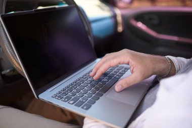 Arabada otururken dizüstü bilgisayarda klavyeyle yazı yazan, dijital göçebe, uzaktan çalışma ve seyahat ederken özgürlük yaşam tarzı kavramını gözler önüne seren erkeklerin yakın çekimi.