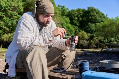 İspanyol adam kahve çekirdeklerini öğütüyor. Seyahat öğütücüsüyle sabah kampında başlamak üzere lezzetli bir içecek hazırlıyor..