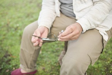 Açık havada bir kütüğün üzerinde oturan çok amaçlı bir araç açan tanınamayan kişi.