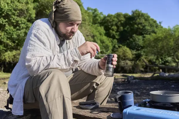 İspanyol adam kahve çekirdeklerini öğütüyor. Seyahat öğütücüsüyle sabah kampında başlamak üzere lezzetli bir içecek hazırlıyor..