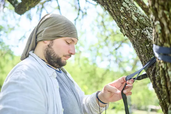 Genç İspanyol adam doğada dinlenmek için ağaçlara hamak asıyor. Kavram: açık havada eğlenmek.