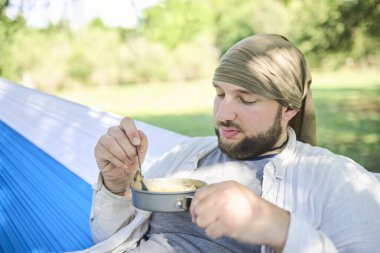 Hamakta oturan genç İspanyol adam dışarıda takılıyor, yemeğinin tadını çıkarıyor. Kamp alanındaki bir gezginin günlük hayatı..
