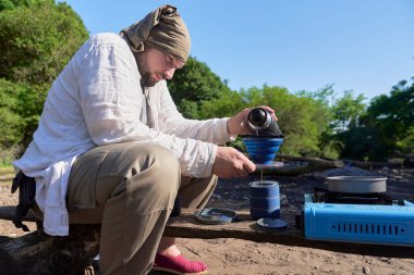 Kamp kahve yapma süreci: İspanyol bir gezgin, kamp alanında kahvaltısını hazırlamak için katlanan seyahat filtresine taze öğütülmüş kahve döker..
