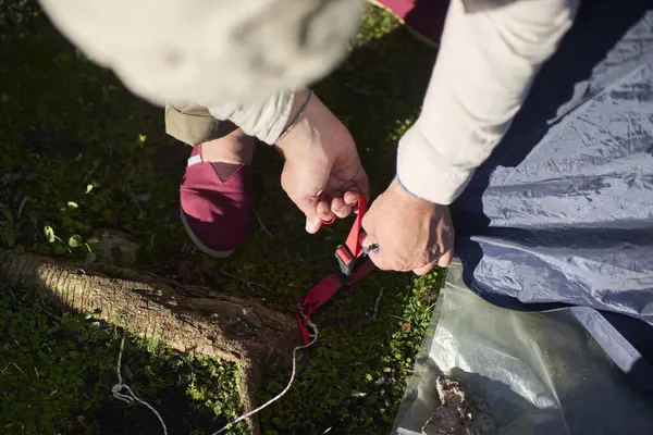 Tanınmayan bir adam çadırını yağmur gibi kuruyor, onu dışarı fırlatma sürecinde. Gün batımı gün ışığı.