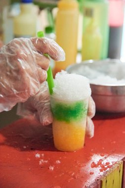 Tanımlanamayan biri yaptığı ahududuna plastik pipet koyuyor. Rengarenk ve ferahlatıcı bir Kolombiya aperatifi. Farklı tatlar, soslar ve soslarla ezilmiş buzdan oluşuyor..