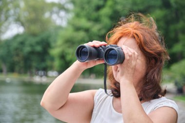 Uzaktan gözlemlemek ve keşfetmek için dürbün kullanan yaşlı bir İspanyol kadının portresi. Kavram: Doğayla temasta aktif bir yaşam tarzı sürdürmenin refahı.
