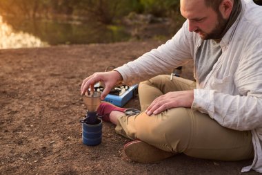 Kahve filtreleme işlemi. İspanyol adam sabahın erken saatlerinde El Palmar Ulusal Parkı, Entre Rios, Arjantin 'de bir dere kenarında kahvaltı hazırlıyor..