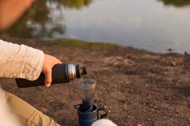 Kahve filtreleme işlemi. İspanyol adam sabahın erken saatlerinde Arjantin 'in Entre Rios kentindeki El Palmar Ulusal Parkı' nda bir derenin kenarında kahvaltıda sıcak su dolduruyor..