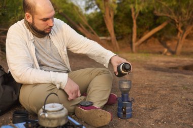 Kahve filtreleme işlemi. İspanyol adam sabahın erken saatlerinde El Palmar Ulusal Parkı, Entre Rios, Arjantin 'de bir dere kenarında kahvaltı hazırlıyor..