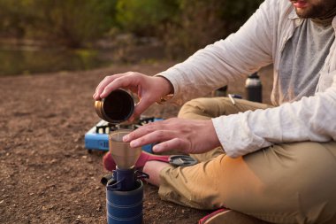 Kahve filtreleme işlemi. Sabahın erken saatlerinde El Palmar Ulusal Parkı, Entre Rios, Arjantin 'de bir derenin kenarında kahvaltı hazırlayan bir adam..