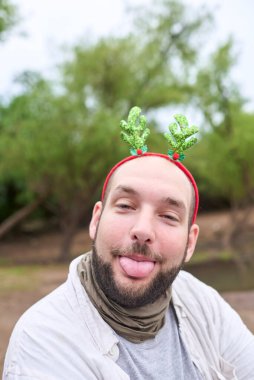 Noel geyiği boynuzu takan genç bir İspanyol adam neşeli bir ifadeyle dilini kameraya uzatıyor..