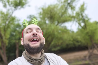 Komik bir Noel geyiği boynuzu takan genç bir İspanyol adam açık havada, doğal bir ortamda komik bir ifadeyle gülümsüyor..