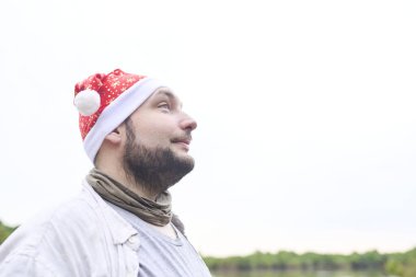 Dışarıda doğal bir manzarada Noel şapkası takan genç bir İspanyol 'un portresi..