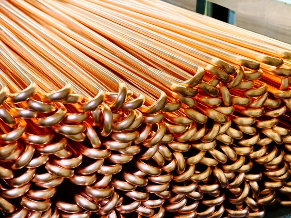 Düzgünce istiflenmiş bakır tüplerden oluşan bir yakın çekim parlak yüzeyi ve pürüzsüz kıvrımlarını sergiliyor. Endüstriyel ve inşaat uygulamaları için ideal.