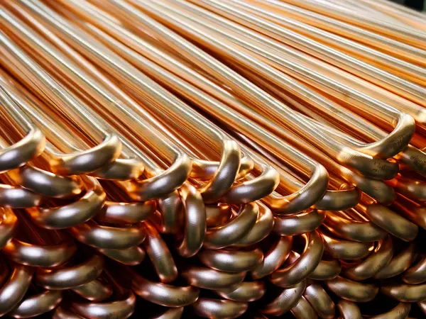 Üretim tesisinde düzgünce istiflenmiş bakır boruların yakın çekim görüntüsü, parlaklık ve pürüzsüz dokularını gözler önüne seriyor, endüstriyel ve tesisat uygulamaları için ideal..