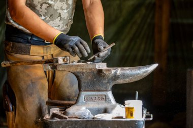 Bir demirci at nalı ile çalışıyor.