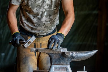 Bir demirci at nalı ile çalışıyor.