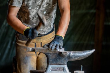 Bir demirci at nalı ile çalışıyor.